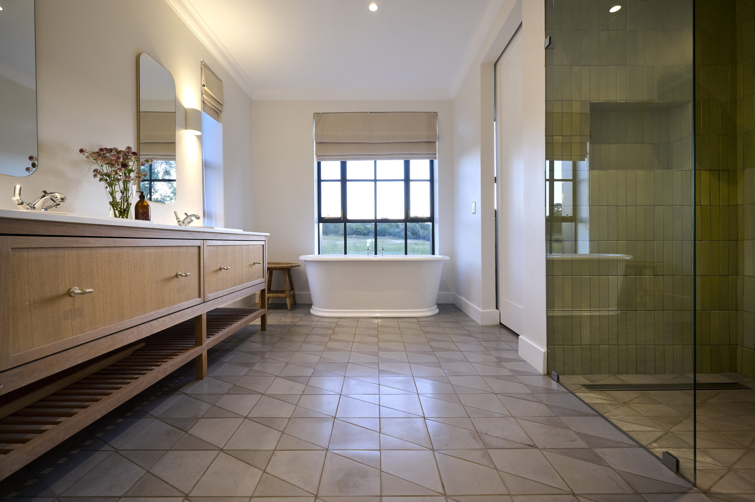 Bright bathroom with a freestanding white bathtub positioned under a black-framed window.