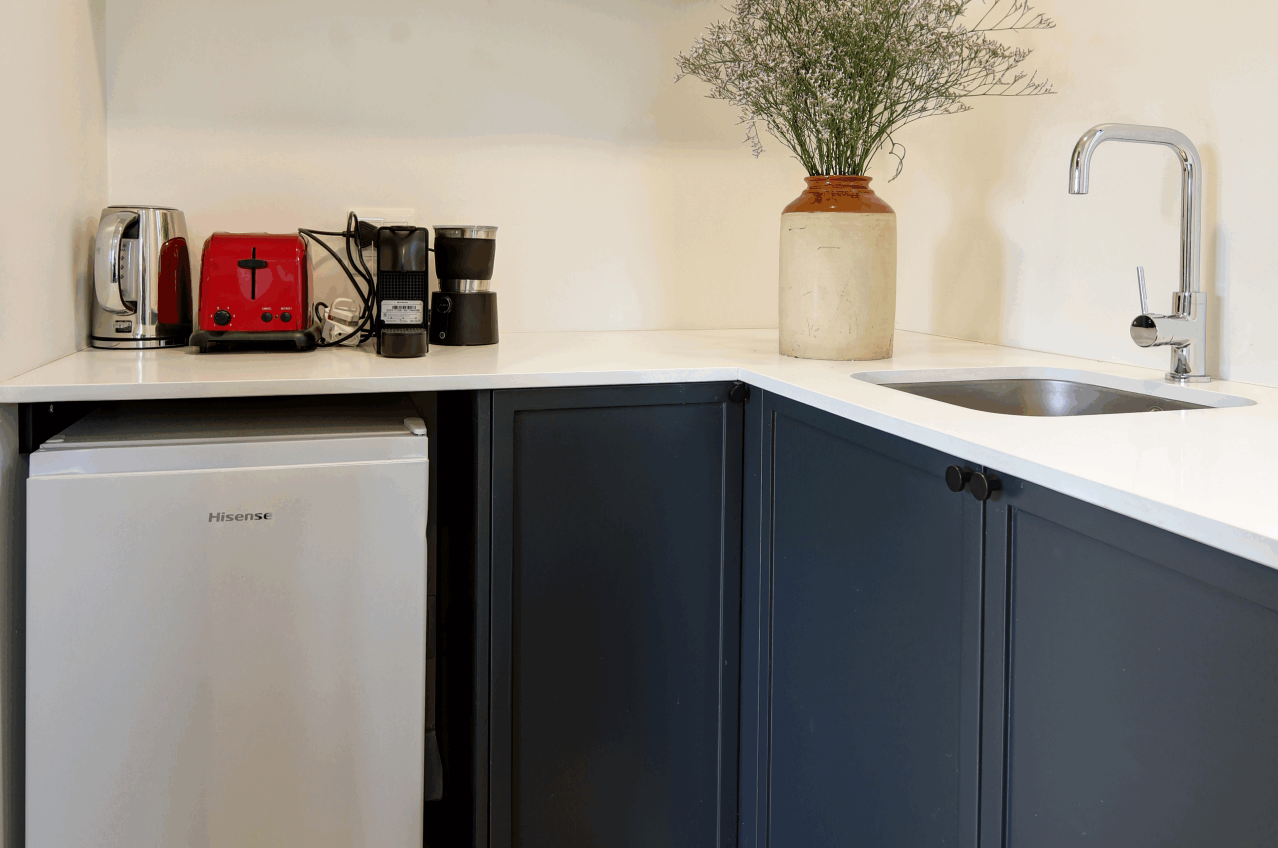 Compact kitchenette corner with dark blue cabinetry.