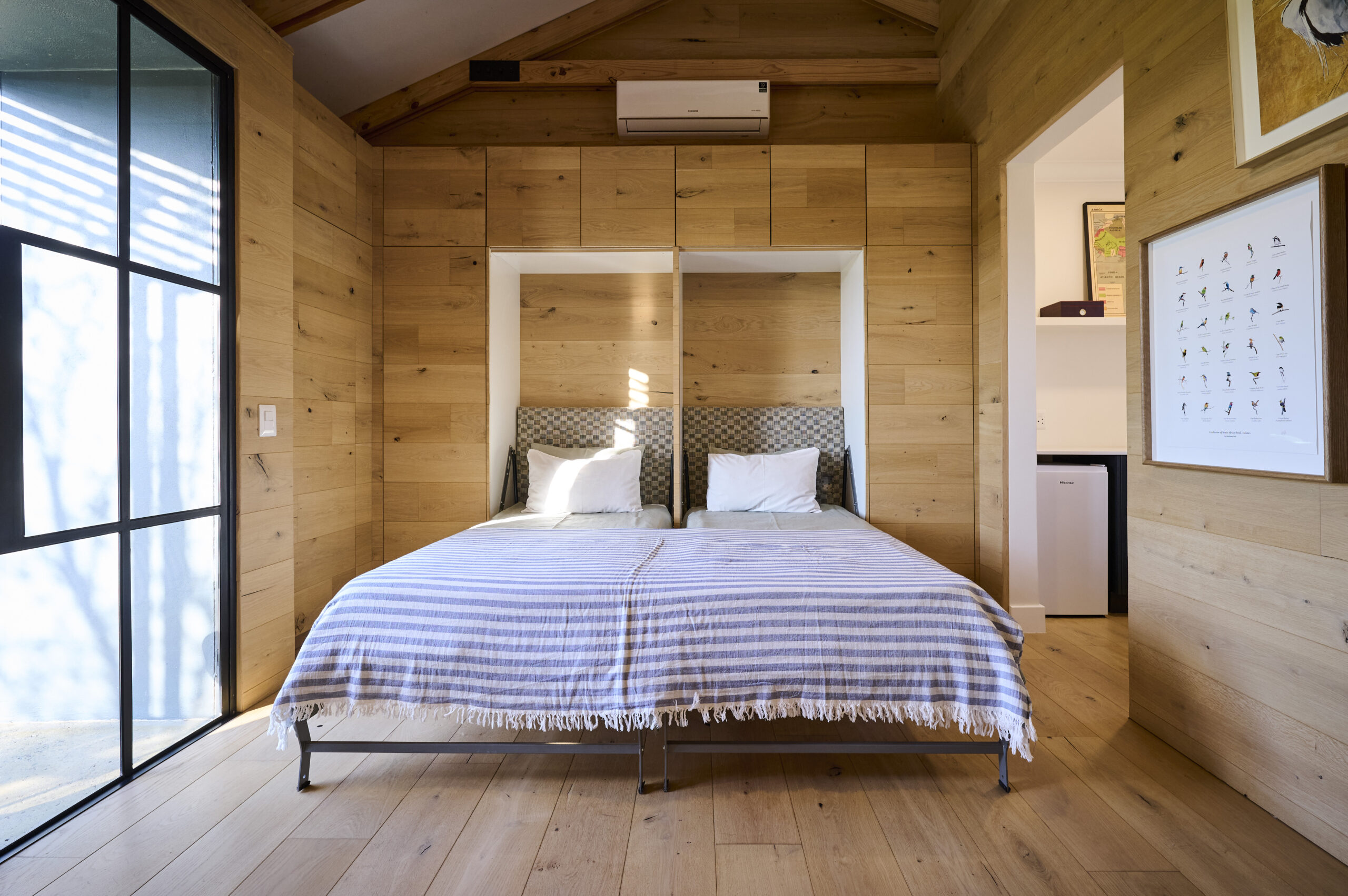Cozy bedroom with light wood-paneled walls and ceiling, featuring two twin beds.