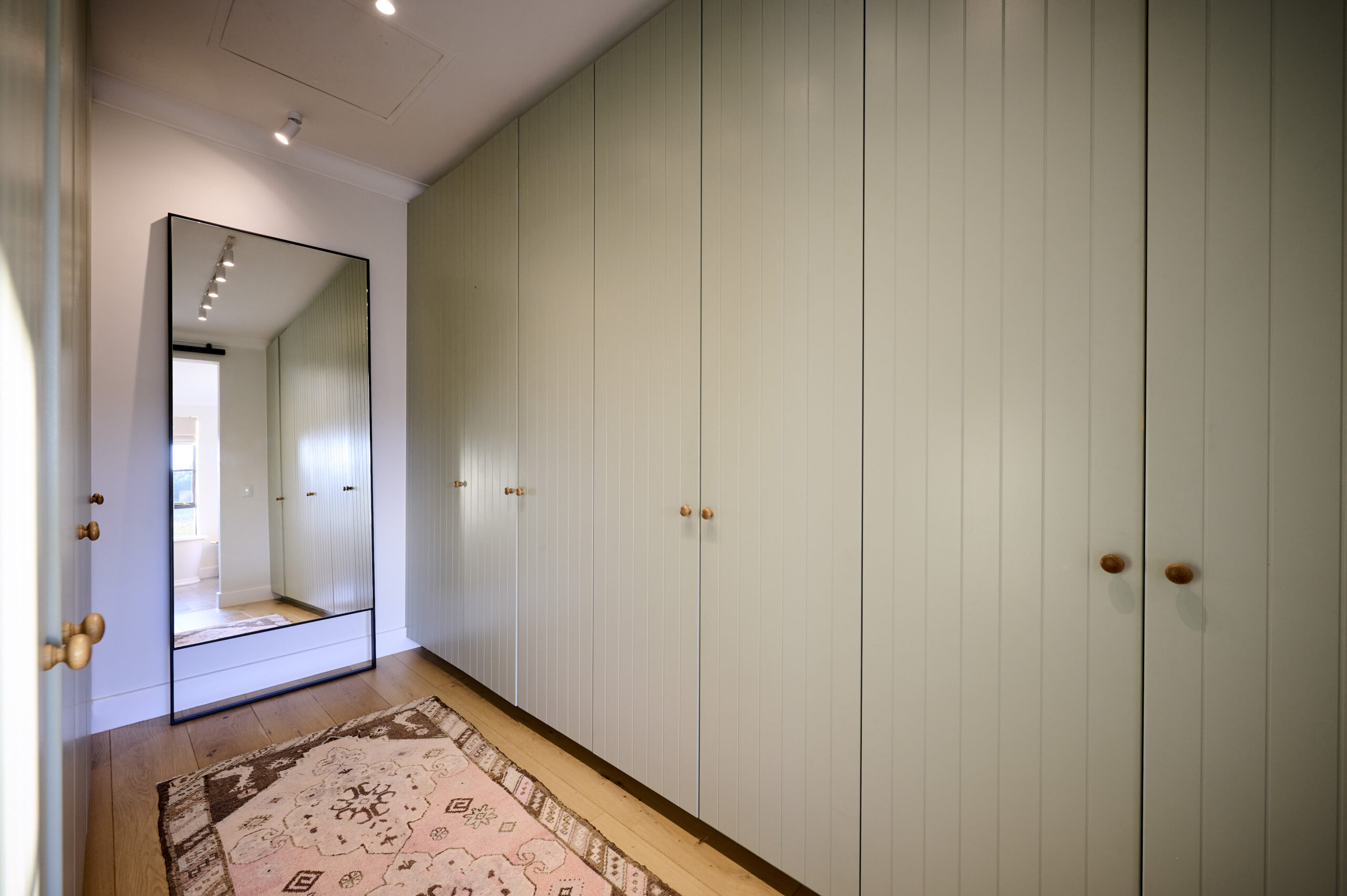 Minimalist floor-to-ceiling olive-gray built-in wardrobes in a dressing area.