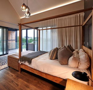 Upper-floor bedroom with large sliding doors leading to a balcony overlooking the Waterfall Estate green belt