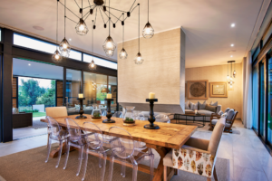 Modern dining area featuring a large timber table and industrial-style pendant lighting near the courtyard garden.
