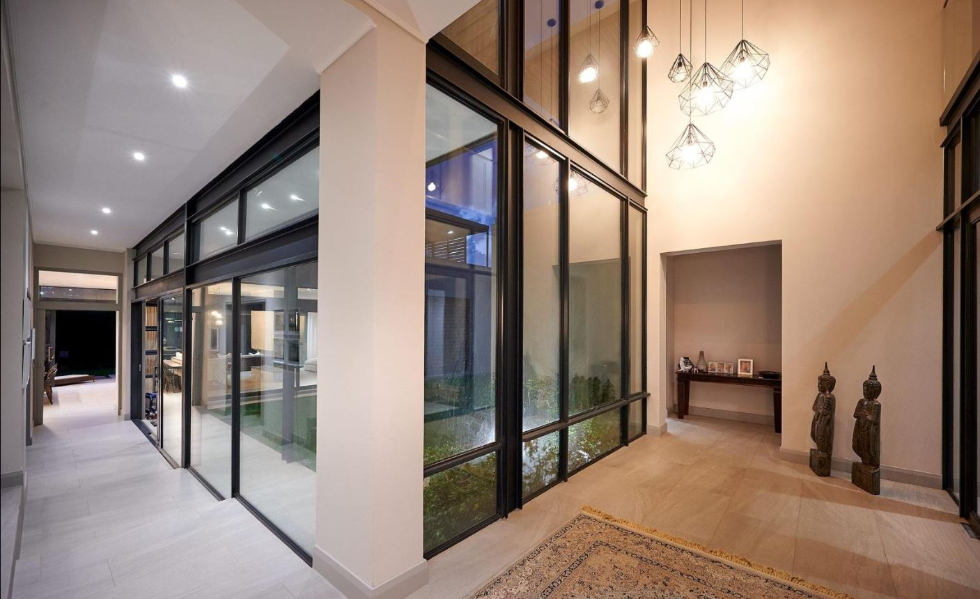 glass-walkway-courtyard-view A bright gallery-style walkway with floor-to-ceiling glass windows overlooking the private inner courtyard