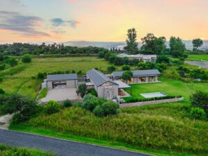 Panoramic aerial shot of the modern home and its extensive grounds under a soft sunset sky.