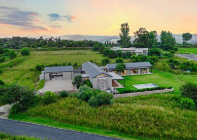 Panoramic aerial shot of the modern home and its extensive grounds under a soft sunset sky.
