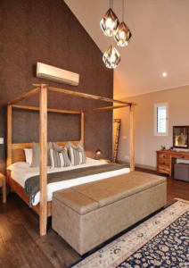 Master bedroom featuring a four-poster bed, vaulted ceilings, and a feature textured wall.