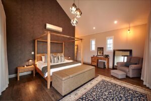 Master bedroom featuring a four-poster bed, vaulted ceilings, and a feature textured wall.