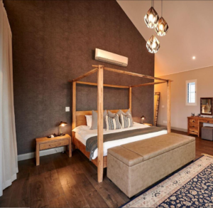 Master bedroom featuring a four-poster bed, vaulted ceilings, and a feature textured wall.