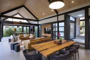 Modern covered patio and entertainment area with high vaulted ceilings and large glass folding doors looking out into the central courtyard.