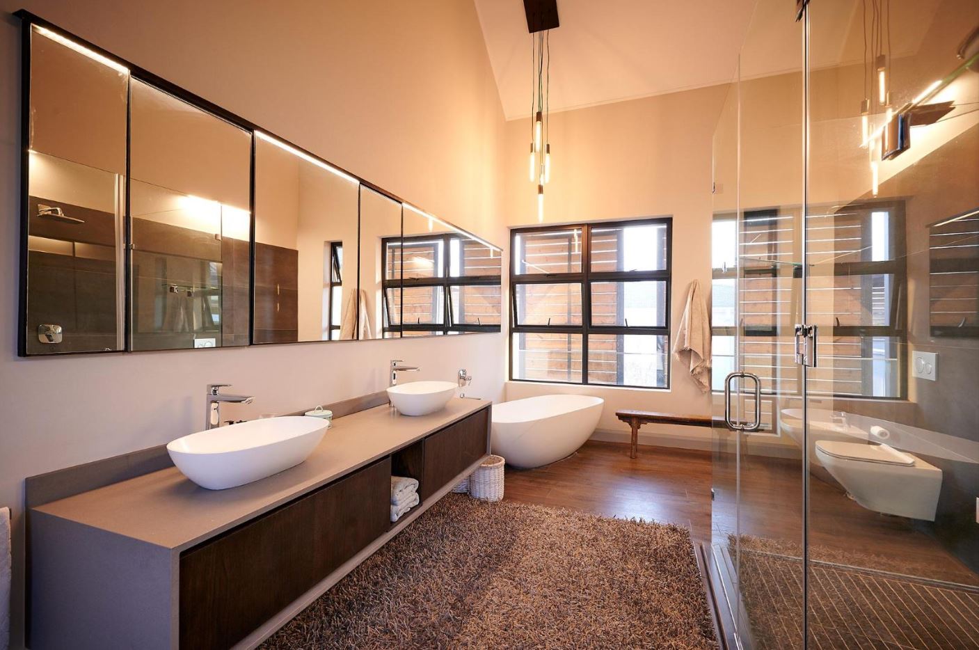 modern-en-suite-bathroom-design Contemporary en-suite bathroom with a double vanity, large mirrors, and a freestanding soaking tub.