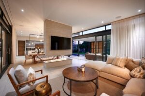 Spacious open-plan living room with a feature fireplace and large glass sliding doors opening to a central courtyard.