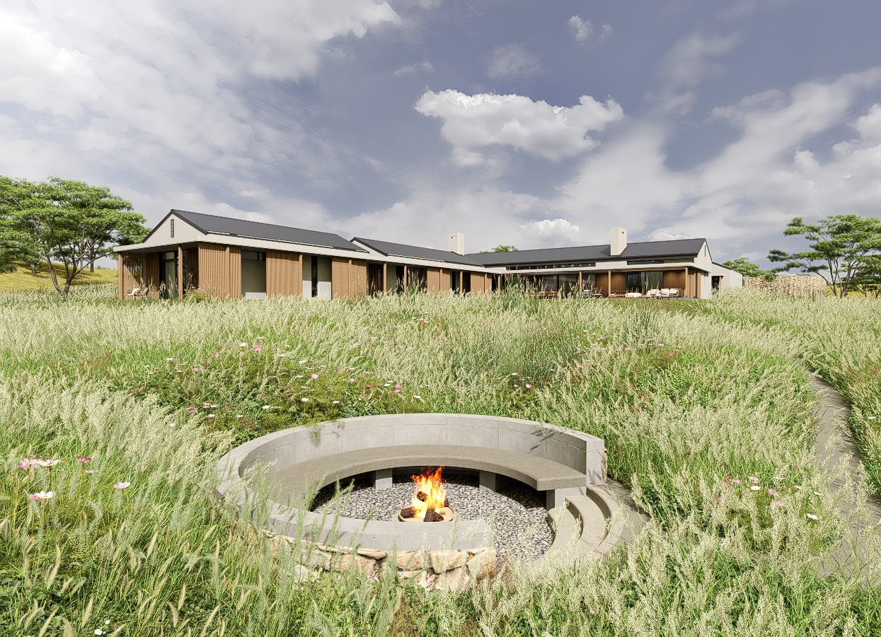outdoor-fire-pit-meadow Sunken circular concrete fire pit with a burning fire, looking up toward the long architectural profile of the house in a meadow.