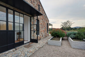 Narrow gravel side path next to the stone wall exterior with raised concrete planter boxes