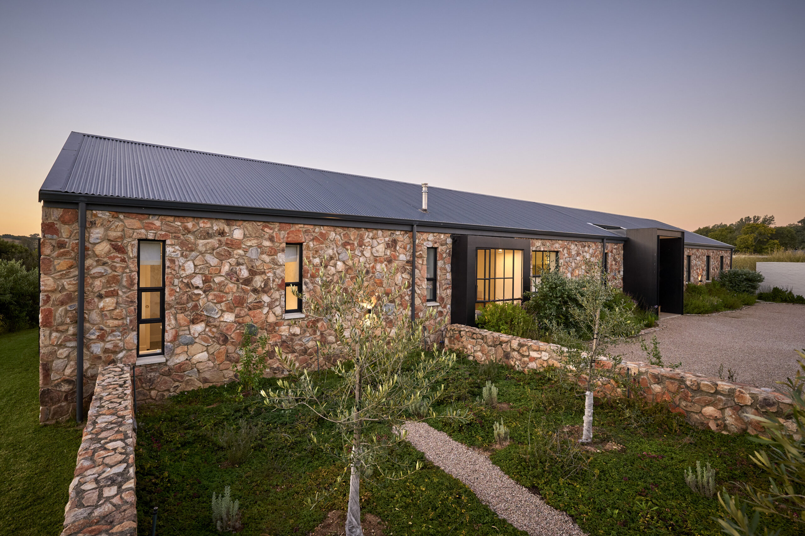 stone-house-walled-garden-exterior High-angle exterior shot of the stone house featuring low stone walls enclosing a garden.
