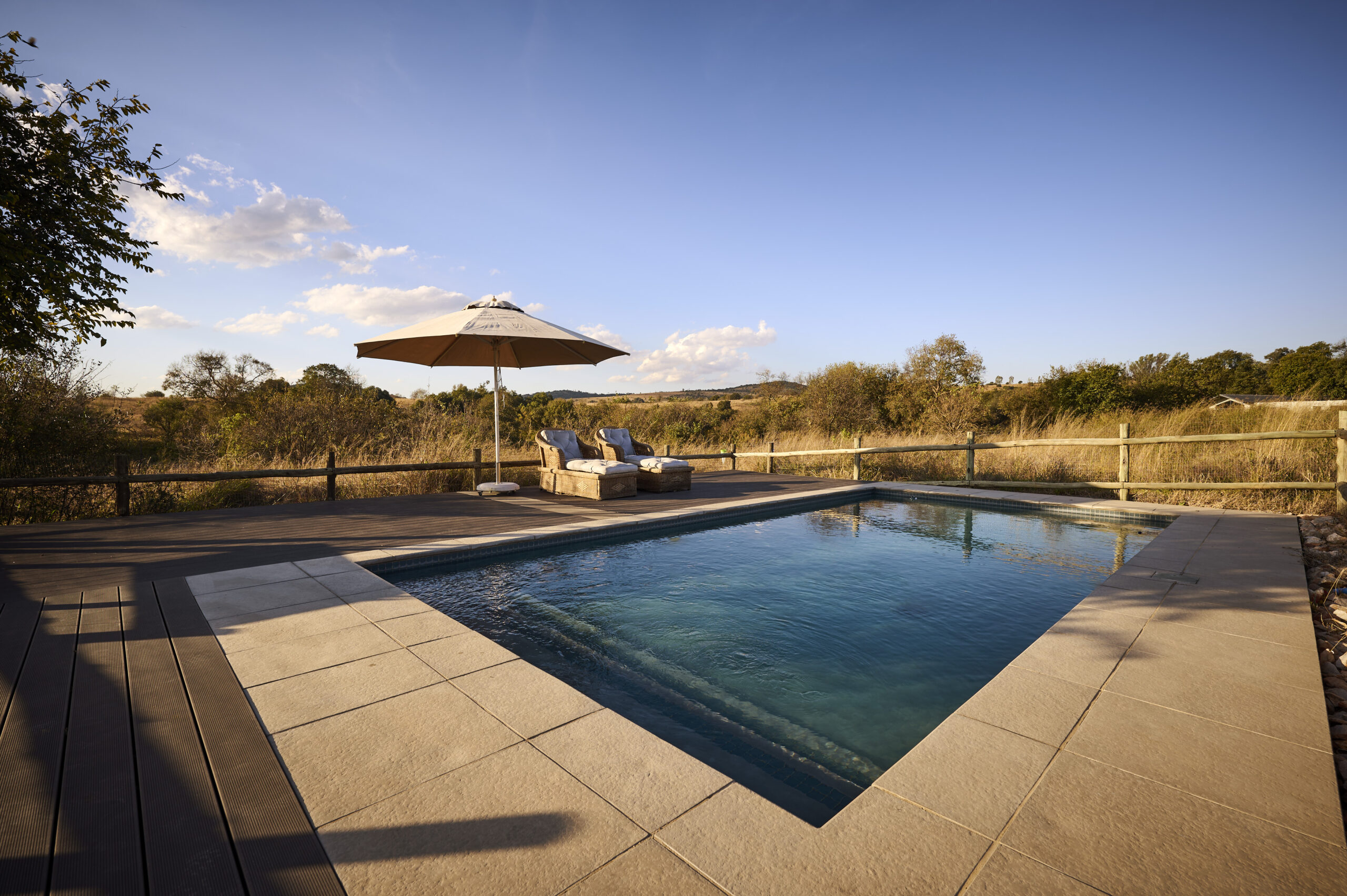 Modern rectangular swimming pool with a concrete deck overlooking a rural landscape.