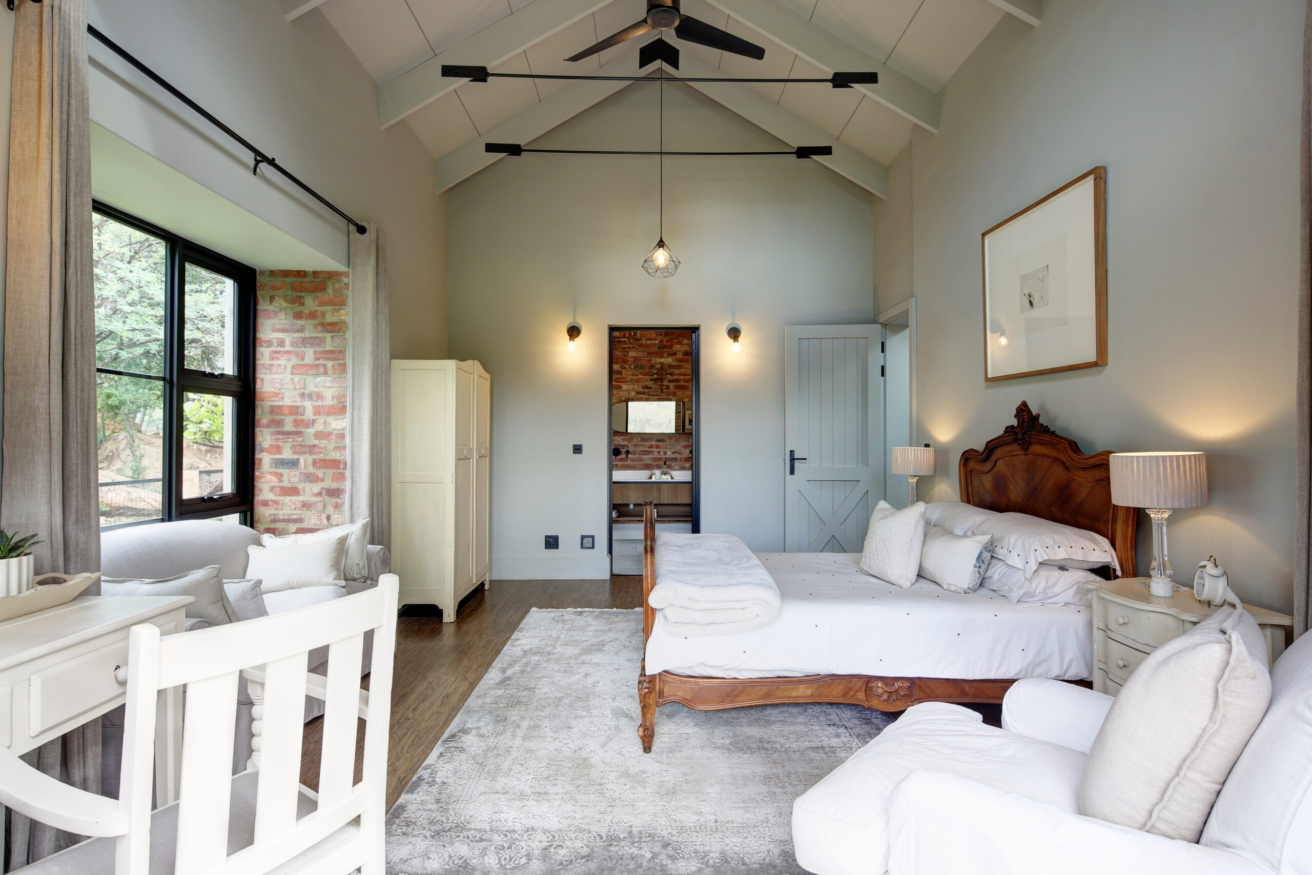 Bedroom with exposed stock brick wall, porthole window and a steel & glass door opening onto private deck