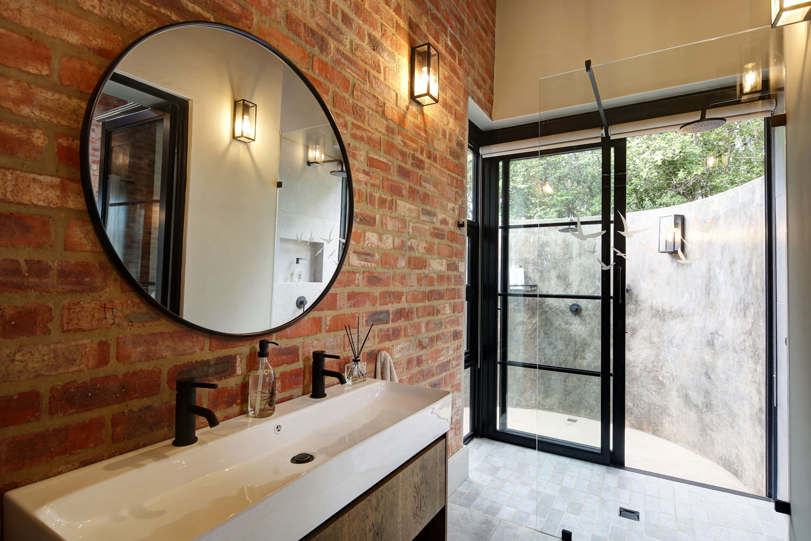 En-suite bathroom with exposed stock brick wall and sliding door opening up onto pop out outdoor shower enclosure