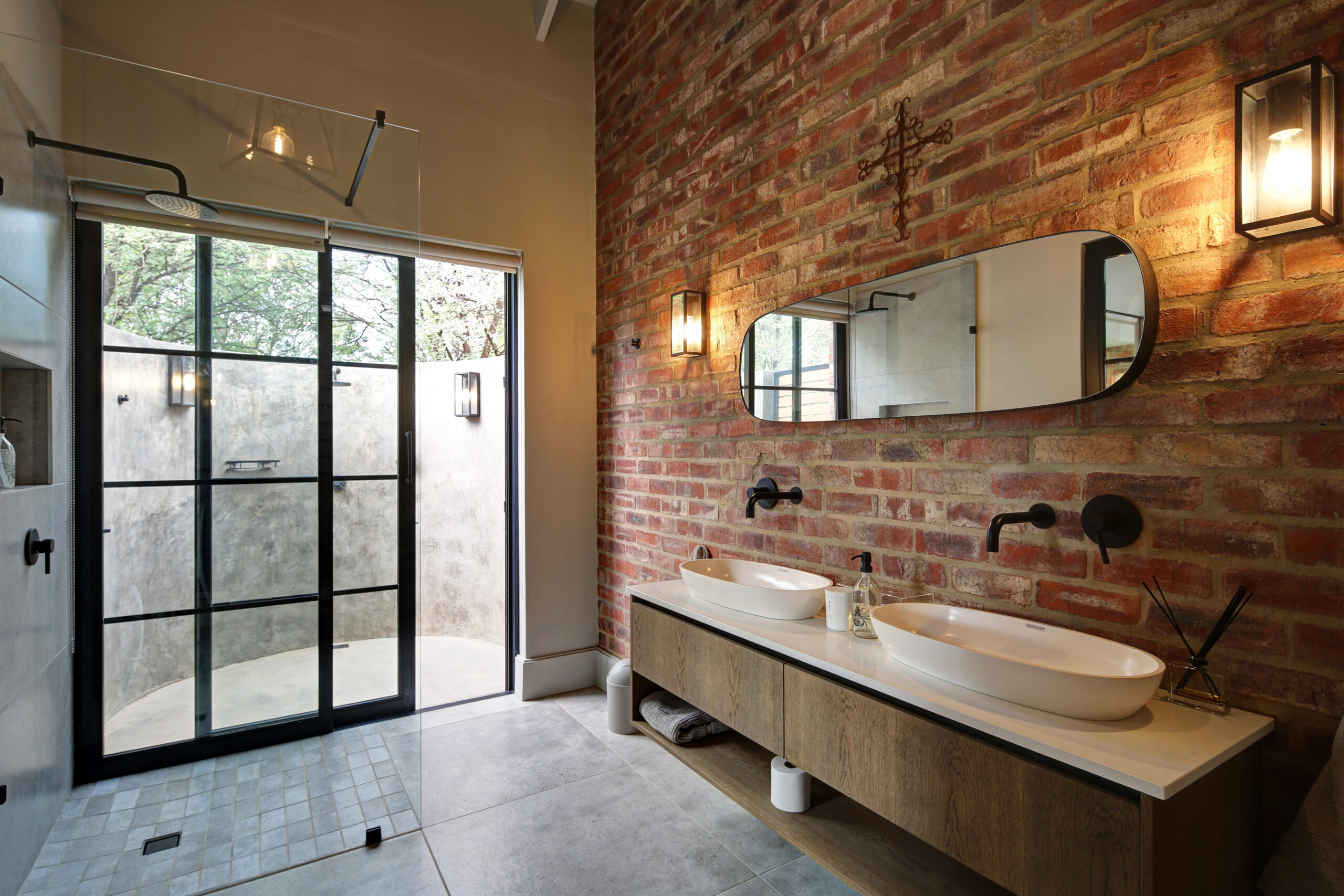 En-suite bathroom with exposed stock brick wall and sliding door opening up onto pop out outdoor shower enclosure