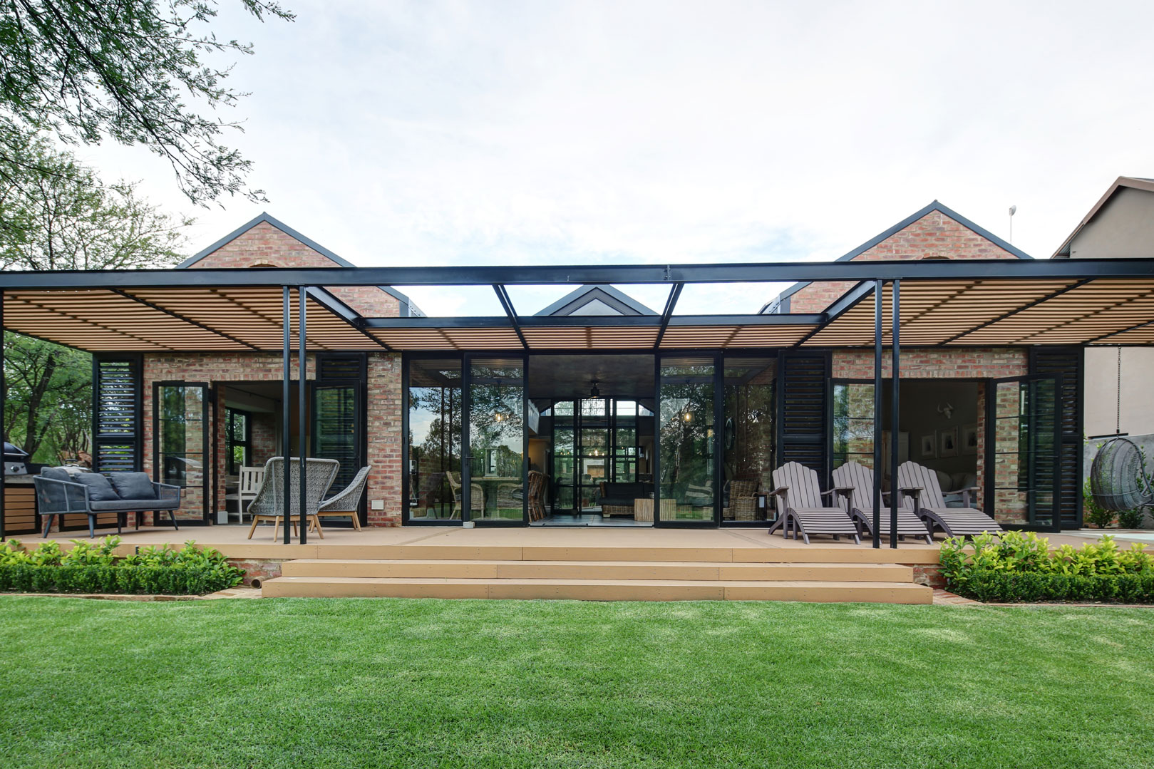 Front view of timber and steel pergola over patio braai area outside bedroom and picture bay window looking toward green belt