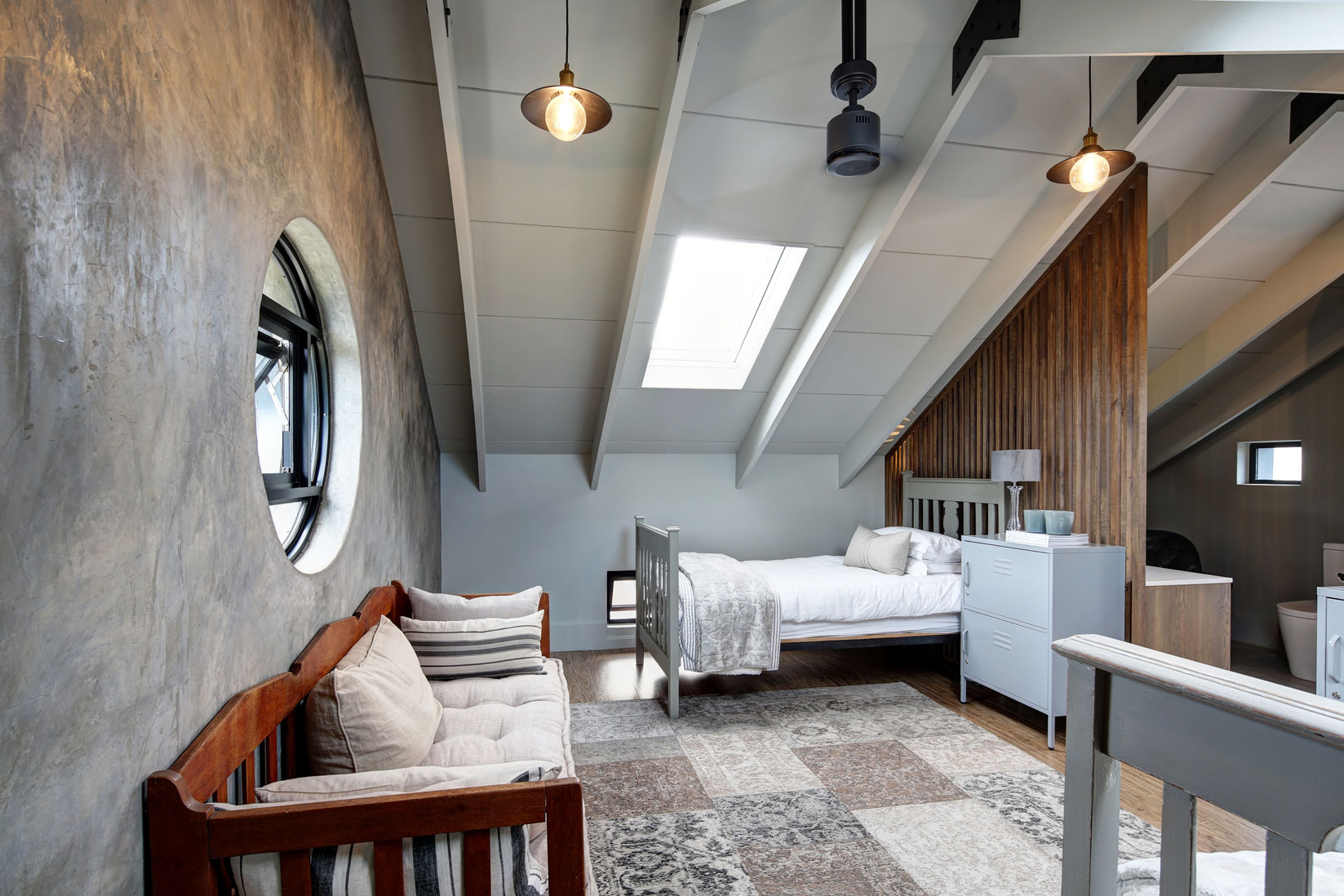 Side view of guest suite with porthole window, pitched roof form and skylight adding light volume to the space