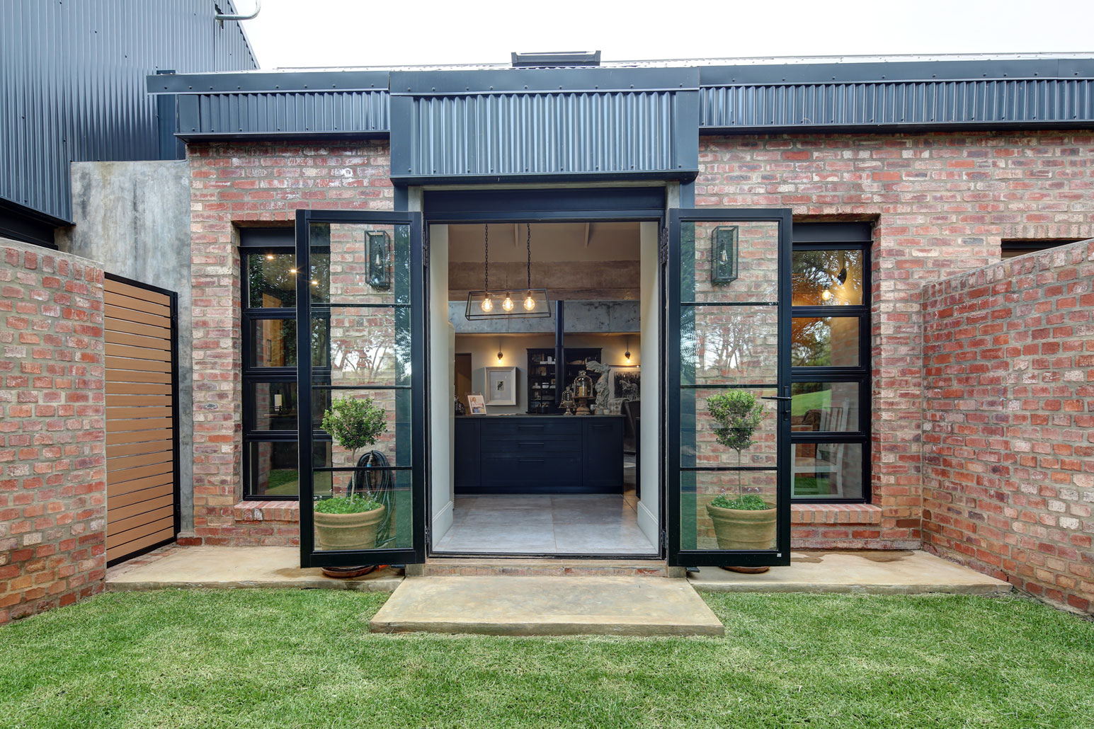 Kitchen porch separated by curved stock brick walls for privacy to bathrooms and outdoor shower