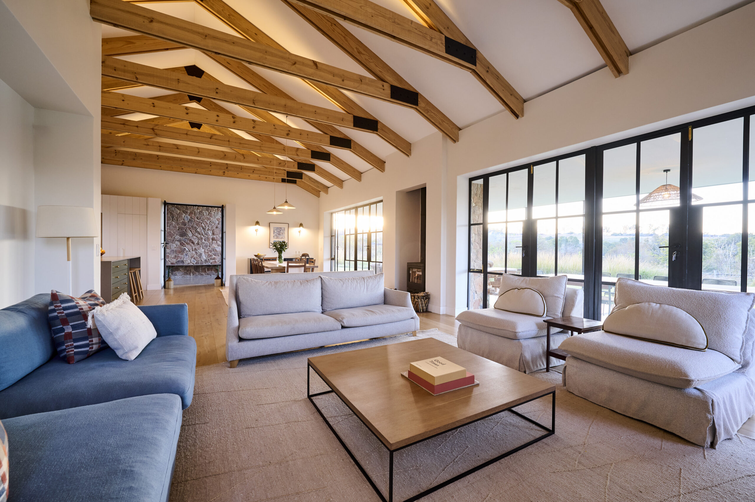 Contemporary Living Room under exposed wooden ceiling trusses with a view of a stone clad fireplace